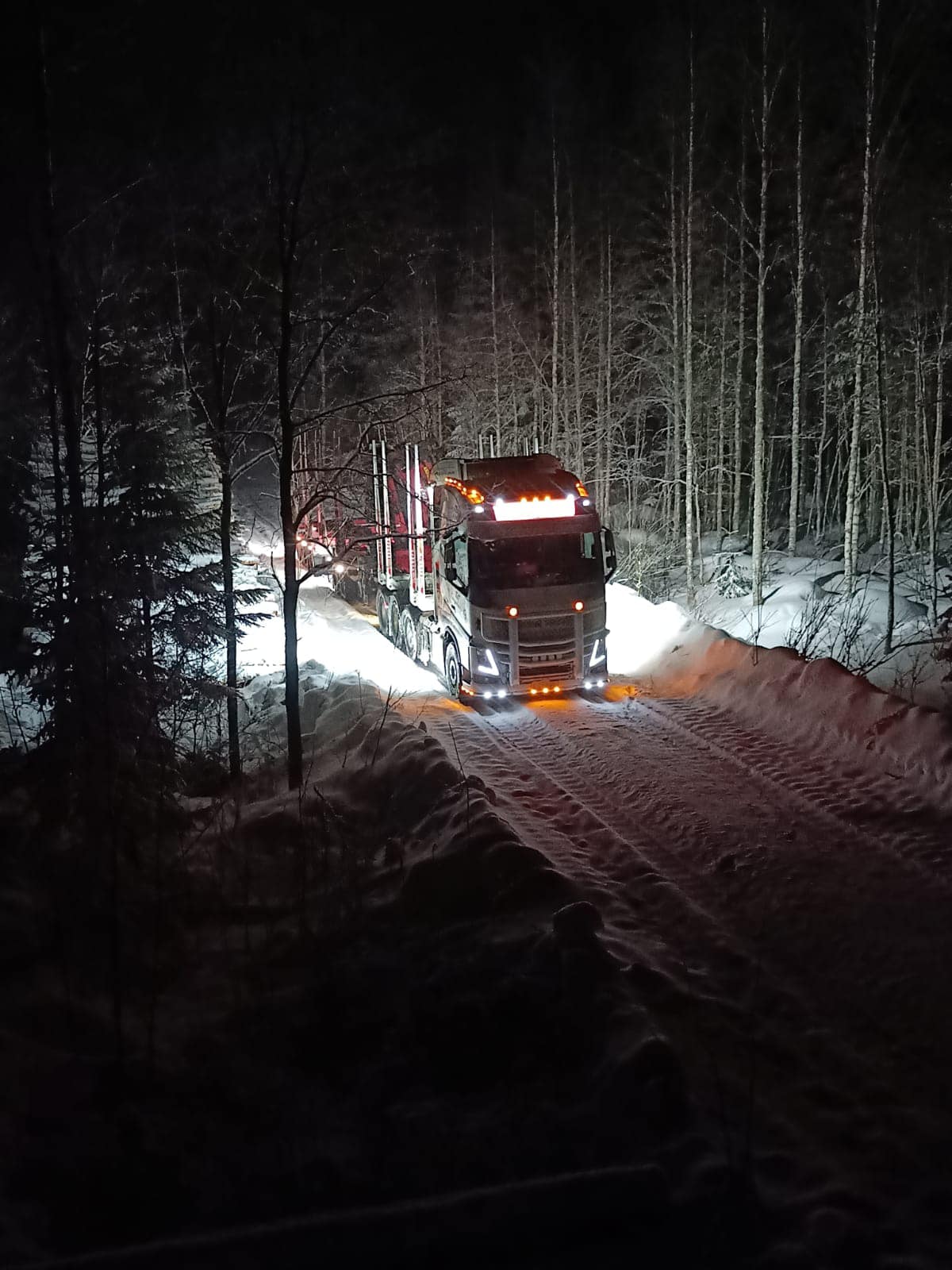 Puuautolla talvisella pimeällä metsätiellä. T&T Kangasharju ajaa puuta yhden puuauton voimin pohjoisessa Suomessa.